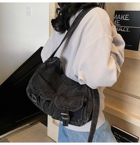 Detail of a vintage black denim motorcycle bag with multi-pocket cargo design and wide strap