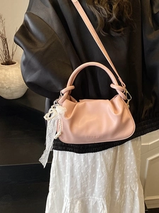 Elegante bolso tipo cubo plisado rosa con colgante de perlas mostrado sobre una modelo