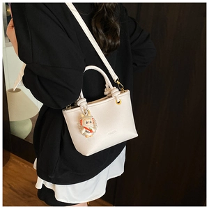 Detailed shot of white lychee leather bucket bag with cute rabbit charm and AMER logo