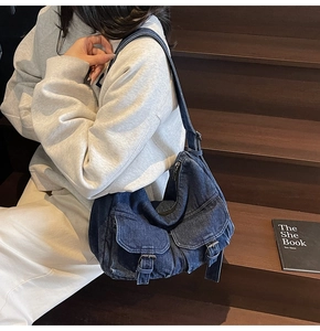 Close-up of deep blue denim shoulder bag with multiple pockets and metal hardware
