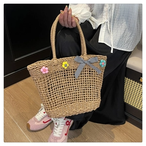 Close-up of straw basket bag with crochet flowers and a black-and-white checkered bow