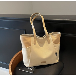 Detail van een grote canvas draagtas met beige stiksels en hoogwaardige lederen accenten