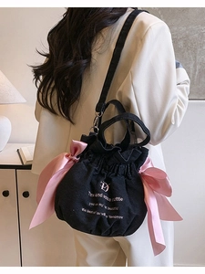 Sac seau en denim noir avec nœuds roses et texte imprimé porté par le mannequin