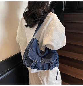 Detail of vintage blue denim hobo bag with front flap pockets and metallic buckles
