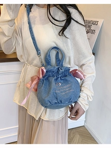 Sac seau en jean bleu avec nœud en satin rose et broderie porté par un mannequin