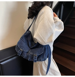 Detail of dark blue denim motorcycle bag with metal buckles on side shoulder view