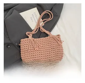 Detail of pink hand-woven bucket bag featuring fringe tassels and braided shoulder strap