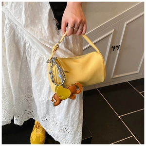 Detail of yellow barrel bag featuring leather elephant charm and litchi grain texture