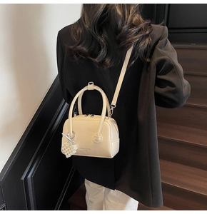Chic cream Boston bag with pearl heart charm shown styled on shoulder with black blazer