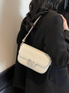 Minimalist cream leather shoulder bag with silver N logo worn by a model