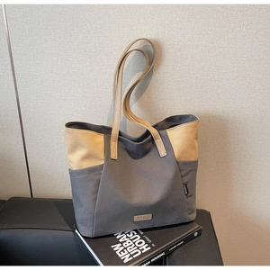 Detailopname van canvas draagtas met contraststiksels en lederen schouderriem