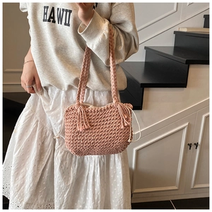 Detail of soft pink woven bucket bag featuring handmade crochet textures and side tassels