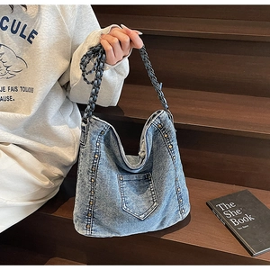 Detail of blue denim tote bag with vintage copper rivets and woven chain strap