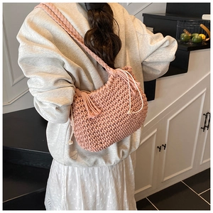 Detail view of pink woven bucket bag featuring drawstring tassels and textured strap