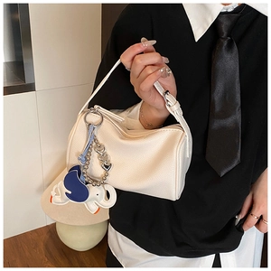 Detail of white lychee-textured cylinder handbag with a blue elephant charm for women