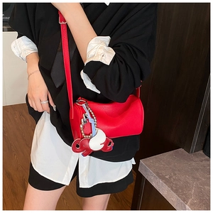 Detail of red lychee leather barrel bag with a cute winged elephant charm pendant