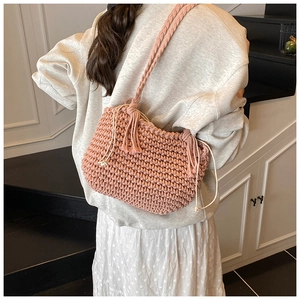 Macro view of pink hand-woven cotton shoulder bag with tassel and drawstring closure