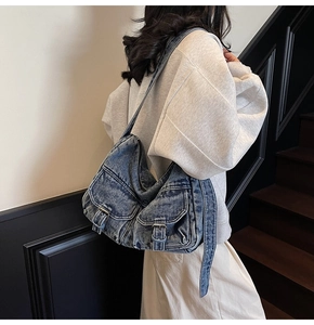 Detailed view of washed denim tote bag with front flap pockets and metal buckles