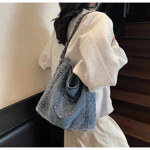 Detail of vintage washed denim crossbody bag featuring metal rivets and chain strap