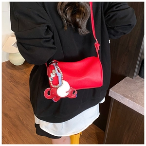 Detail view of red textured leather cylinder bag featuring a cute elephant charm