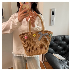 Detail of hollow straw tote bag featuring colorful sunflowers and a gingham bow accent