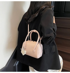 Pink Boston bag with heart pearl charm shown on model in a crossbody style