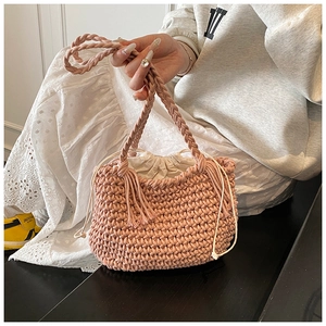 Macro view of woven pink bucket bag featuring thick braided handles and drawstring lining