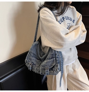 Close-up of vintage blue denim underarm bag featuring double pockets and metallic buckles