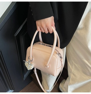 Detail of light pink leather pillow bag with pearl bow charm and shoulder strap