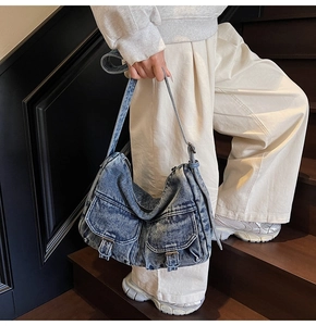 Close-up of vintage blue denim shoulder bag with double pockets and metal buckles