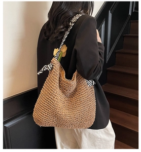 Detail of straw shoulder bag with woven mesh design and black and white striped scarf