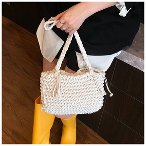 Detail of white hand-woven bucket bag featuring intricate crochet texture and side tassels
