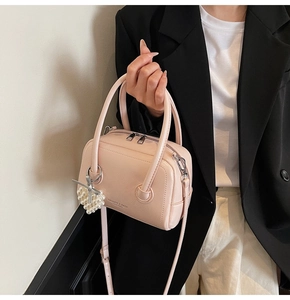 Detail of light pink mini pillow bag with pearl heart pendant and leather texture