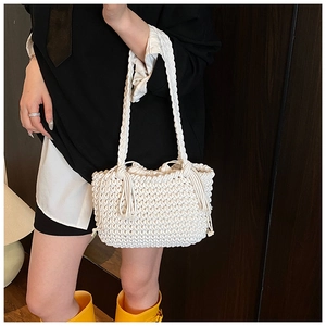 Detail of white woven bucket bag with thick rope handles and bohemian side tassels