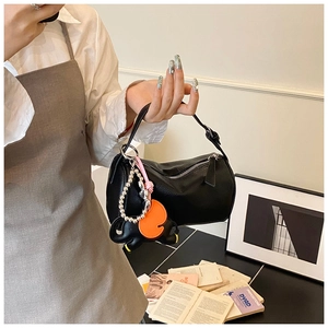 Detail of black pebbled leather boston bag with a unique elephant charm and orange tag
