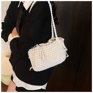 Detailed close-up of white macrame bucket bag with fringe tassels and woven texture