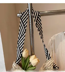 Close-up of beige straw woven shoulder bag with stylish black and white patterned strap
