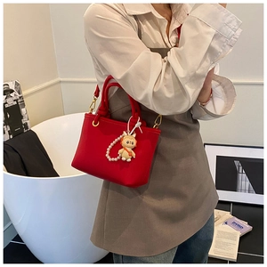 Detail of red lychee textured bucket bag featuring a cute cartoon pearl charm accessory