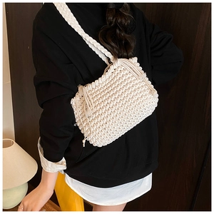 Detail of white hand-woven bucket bag featuring thick cotton rope texture and tassels