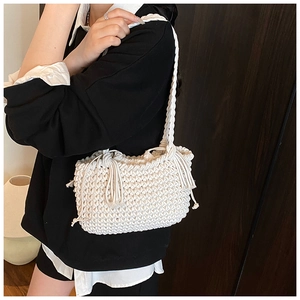 Detailed view of the woven white shoulder bag featuring bohemian tassels and thick texture