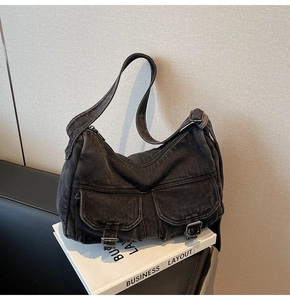 Detail of vintage black denim hobo bag with dual flap pockets and metallic buckle accents