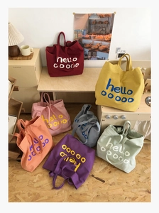 Grote canvas draagtassen in meerdere kleuren met artistieke belettering in een huiselijke sfeer