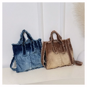 Détail d'un sac cabas en jean avec bords effilochés et texture en dégradé de bleu
