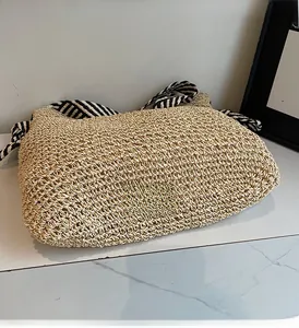 Close-up of handmade straw tote bag with black and white striped webbing handles