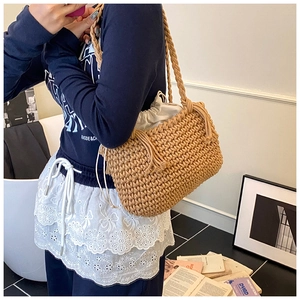 Detail of woven bucket bag with drawstring liner showing texture and shoulder strap