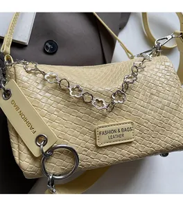 Close-up of woven cream leather boston bag with floral silver chain and leather tag