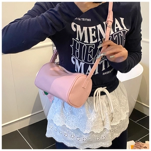 Detail of pink cylinder crossbody bag showing pebbled leather texture and silver zipper