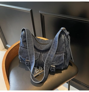 Detail of vintage denim motorcycle bag with silver buckles on double front pockets