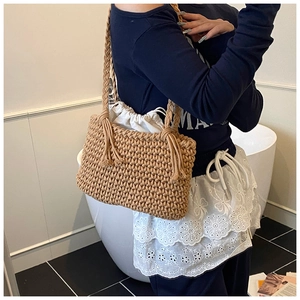 Detail of woven straw bucket bag featuring a white drawstring liner and rope shoulder strap