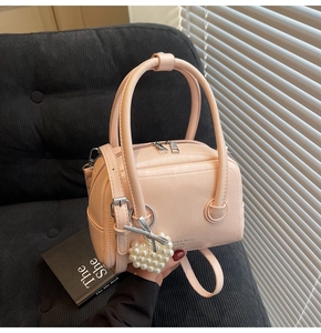 Detail of light pink Boston bag with pearl heart pendant and silver double zippers